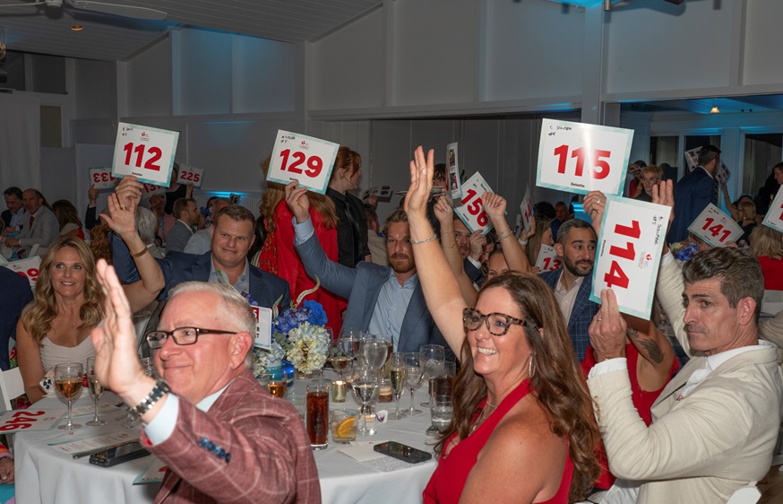 Table full of guests holding up bidder numbers.
